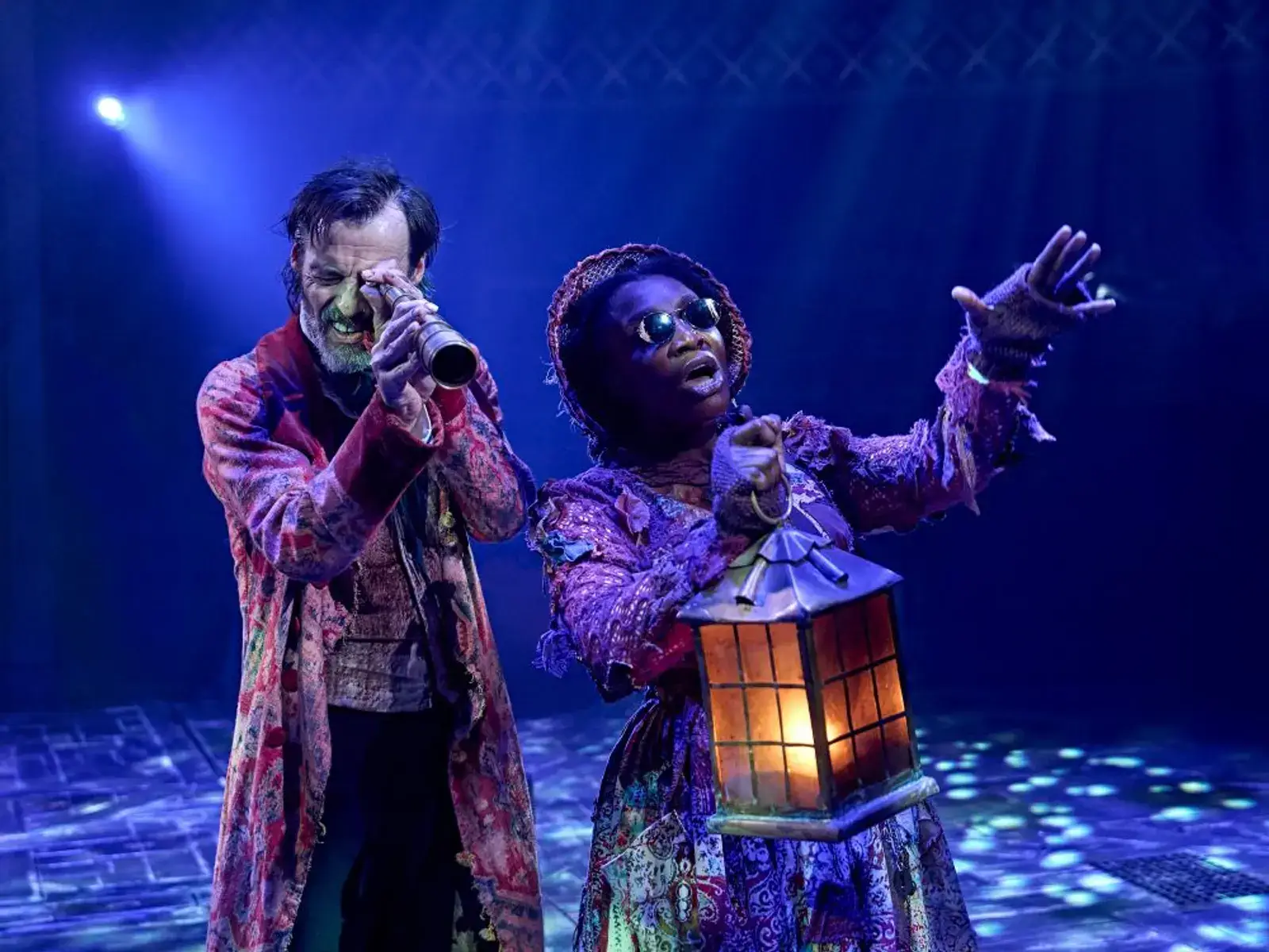 Scrooge is led through the night by a spirit, lantern in hand