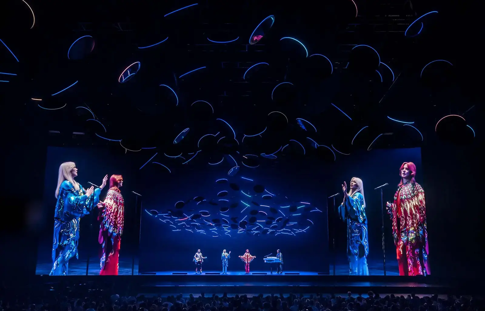 The ABBAtars in sequined kimonos with the live band on stage