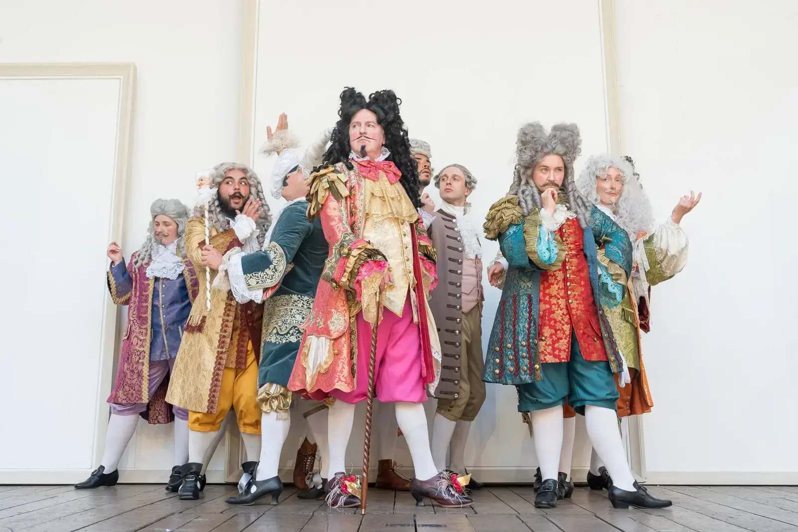 The company in Restoration-era wigs and brocade in the opening court scene