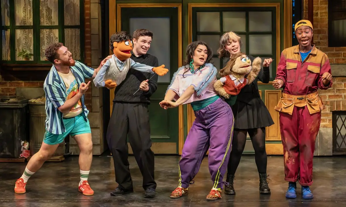 The cast performing a street scene with Princeton and Kate Monster puppets in Avenue Q at the Shaftesbury Theatre, London