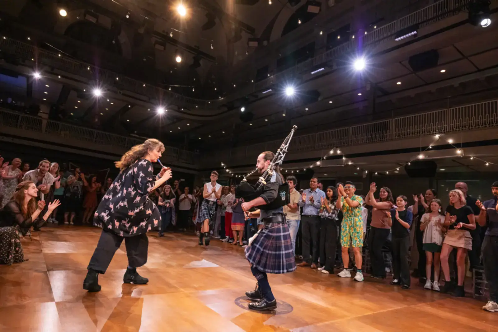 A piper performs as the crowd claps along