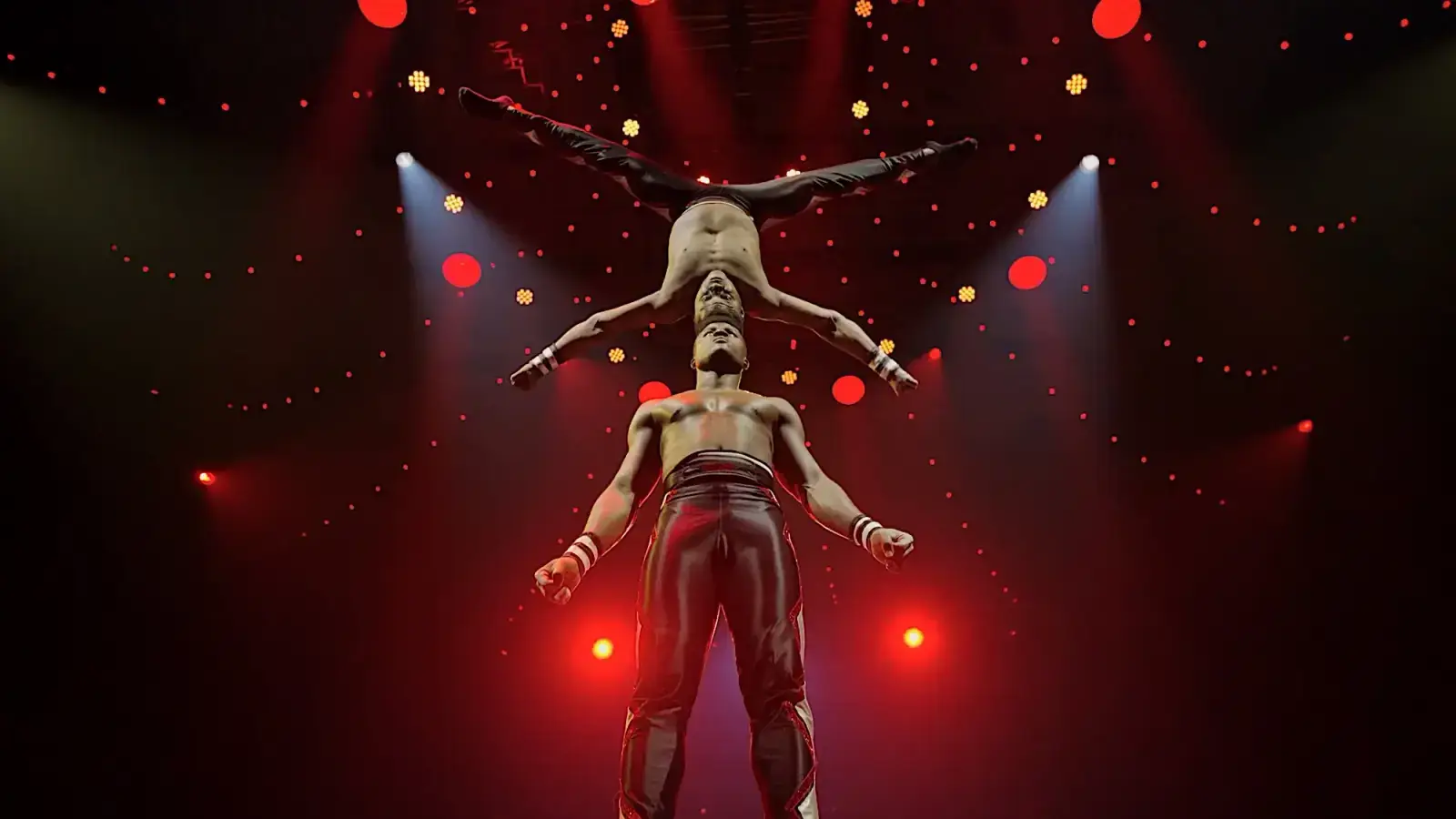 A hand-to-hand acrobatic balancing tower under red light