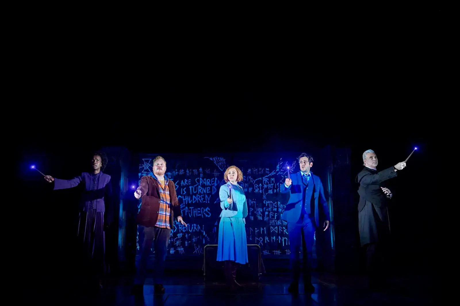 The company cast lit blue wands against a chalk-scrawled wall