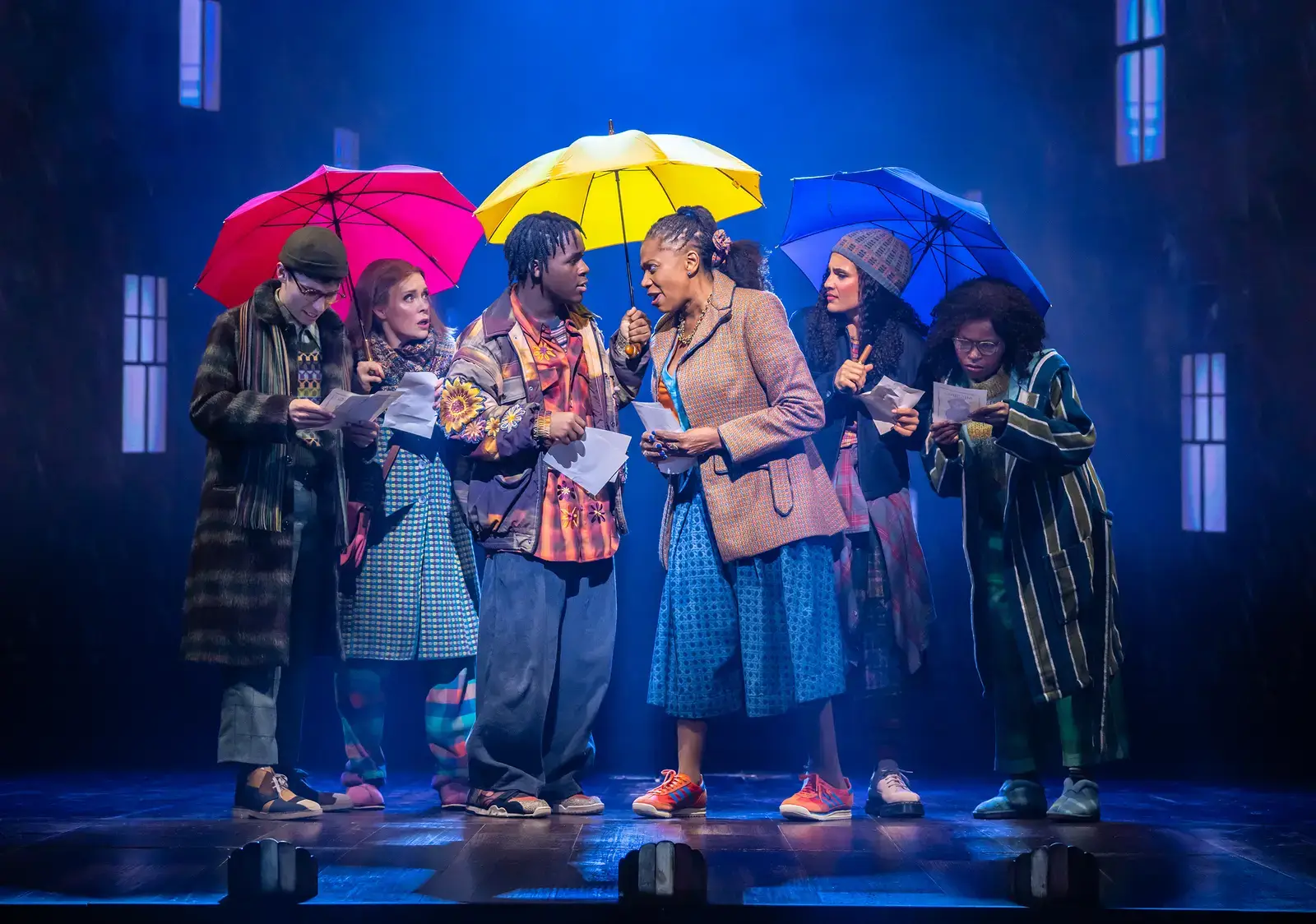 The company under umbrellas in a rain-lit street scene
