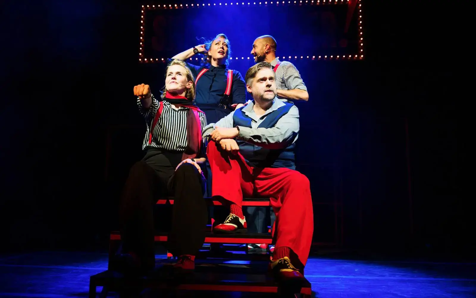 Four company members in a blue-lit tableau