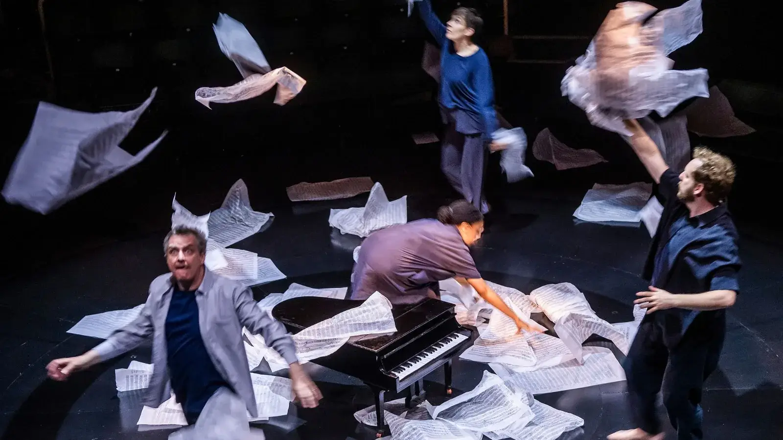Phelim McDermott and the ensemble amid a storm of sheet music