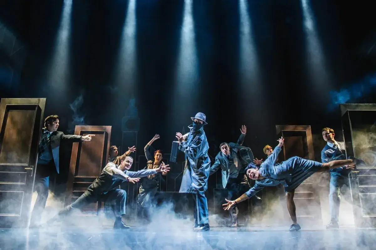 The company emerging through doors in smoke and spotlights in The Comedy About Spies - photography by Matt Crockett & Mark Senior