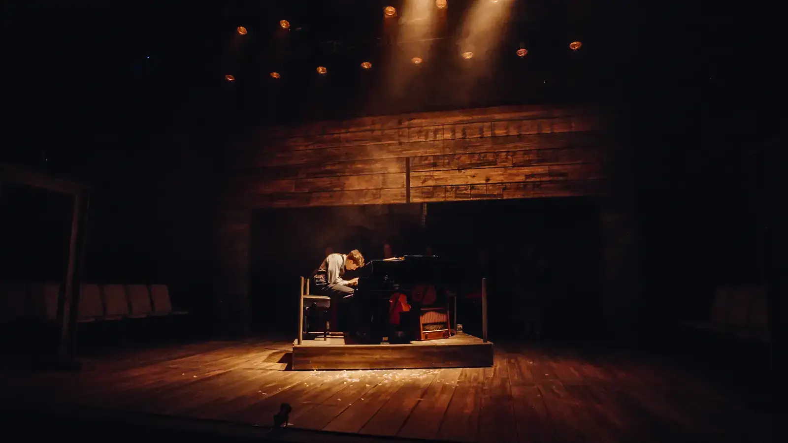 Szpilman alone at the piano in a single spotlight