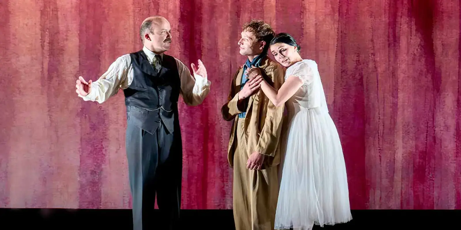 Rory Kinnear, Thomas Flynn and Natalia Osipova in a scene against a red backdrop